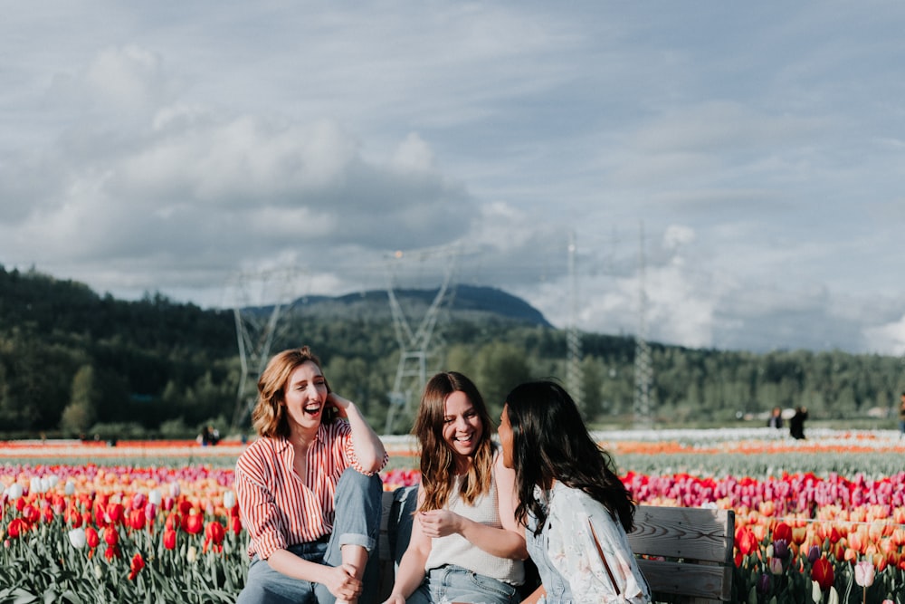 花の近くのベンチに座っている 3 人の女性