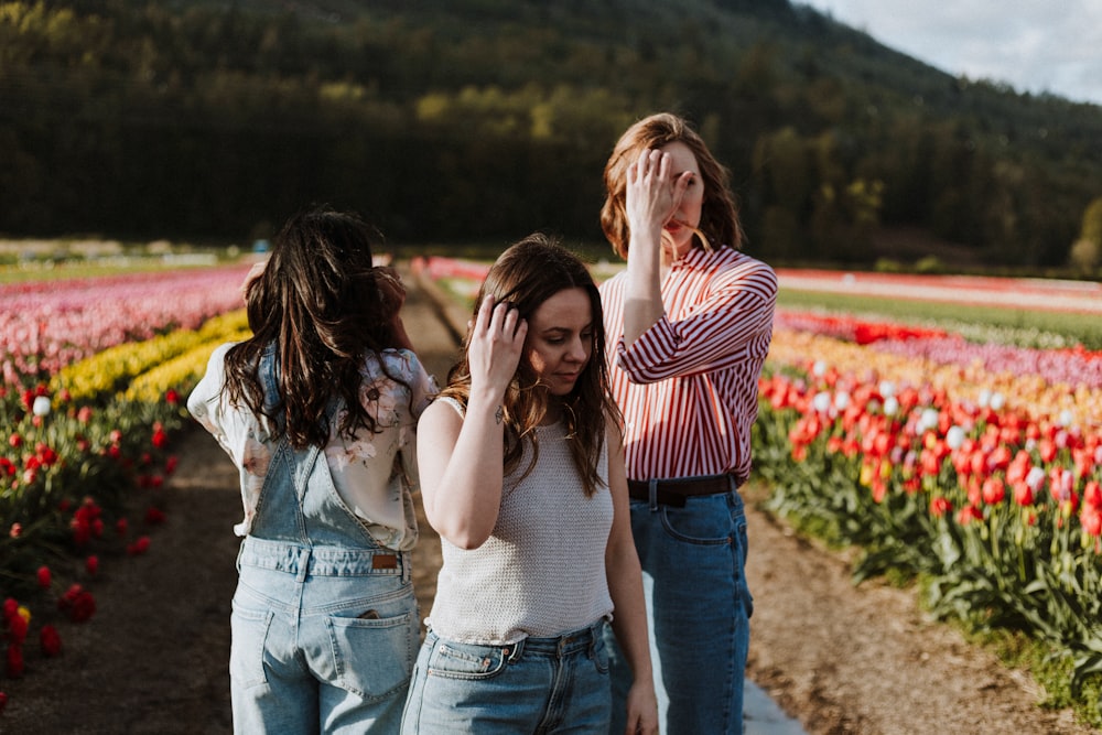 three women standing between flower garden