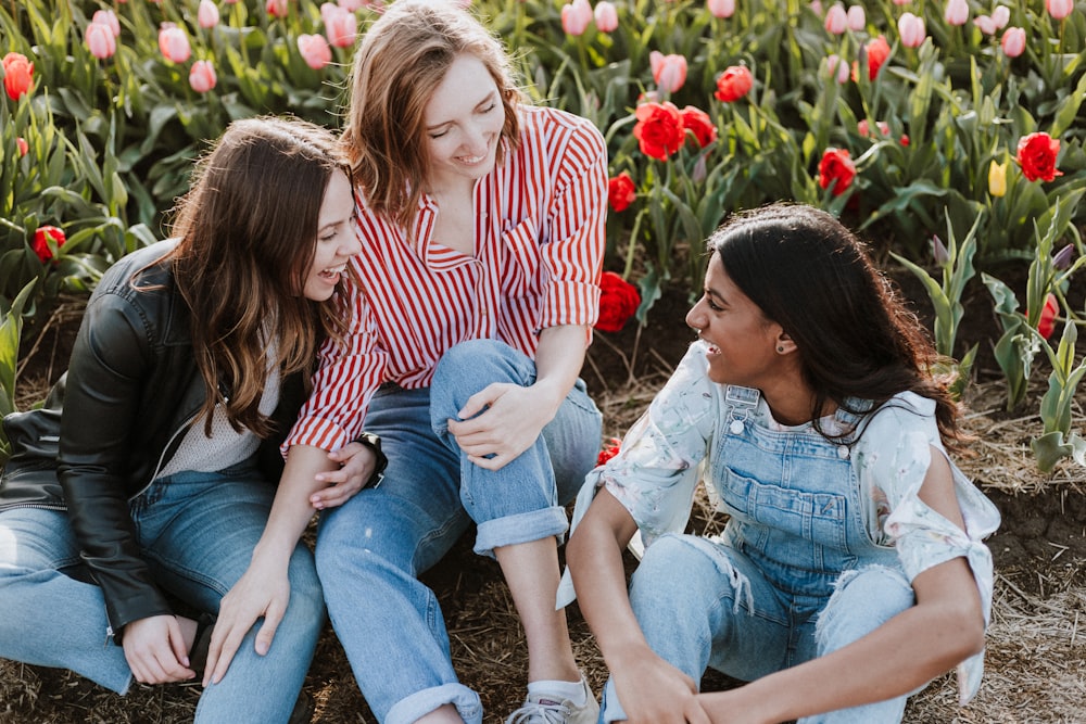 three woman sitting near the flower