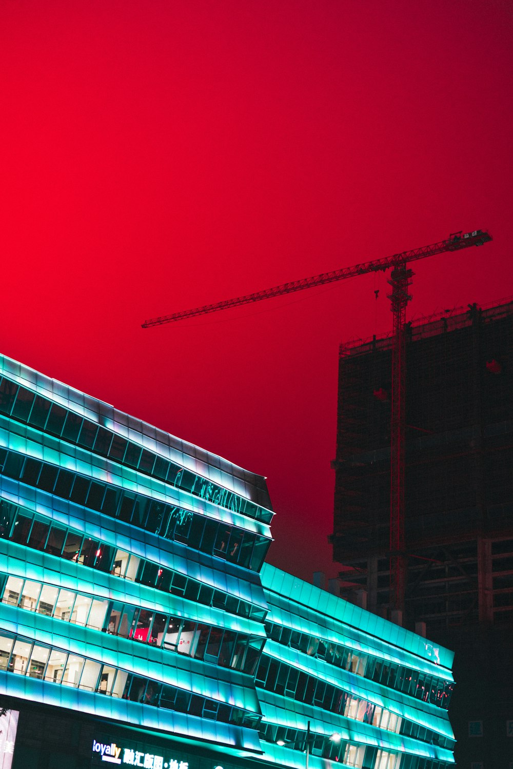 grúa torre entre edificios bajo cielo rojo