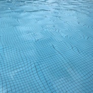Modern blue-tinted pool with crystal clear water reflecting sunlight