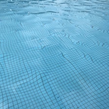 Modern blue-tinted pool with crystal clear water reflecting sunlight