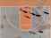 A top-down view of a basketball court with several players engaged in a game. The court features a distinctive orange and blue color scheme, and the shadows cast by the players suggest a sunny day. The basketball hoop, lines of the court, and multiple players in motion are clearly visible.