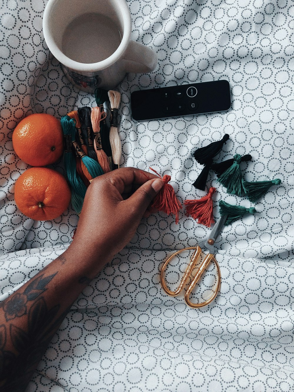 a person's hand holding a pair of scissors next to oranges