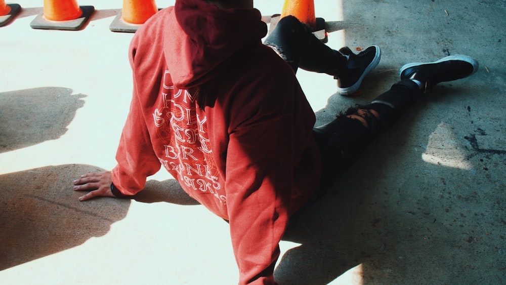 a person in a red hoodie sitting on the ground