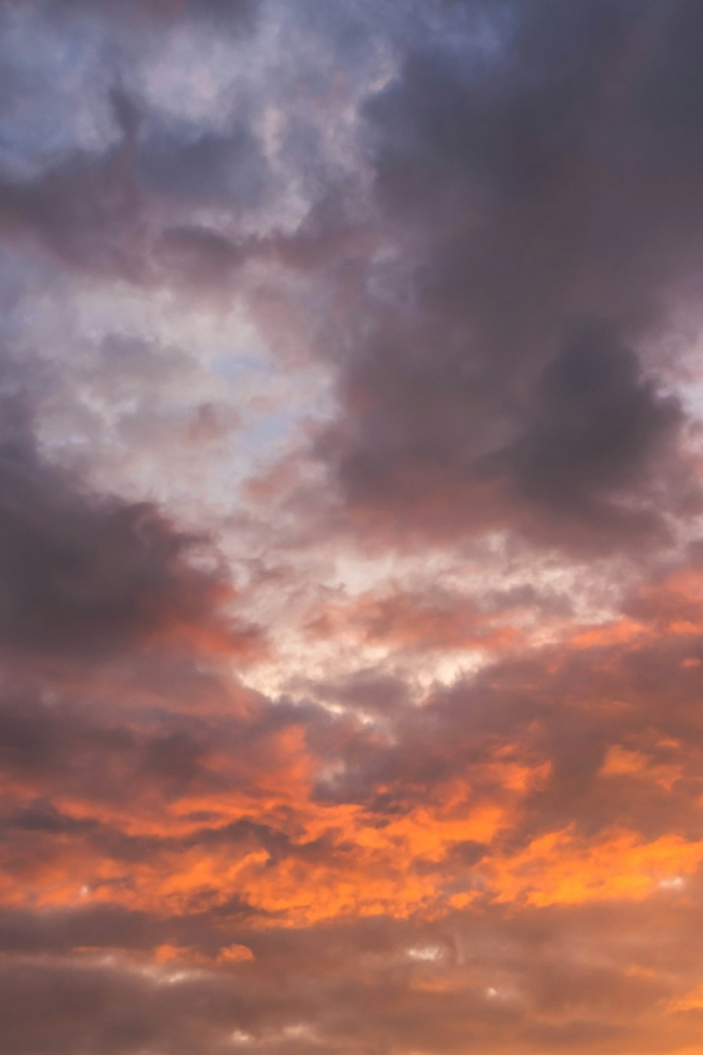 a plane flying through a cloudy sky at sunset