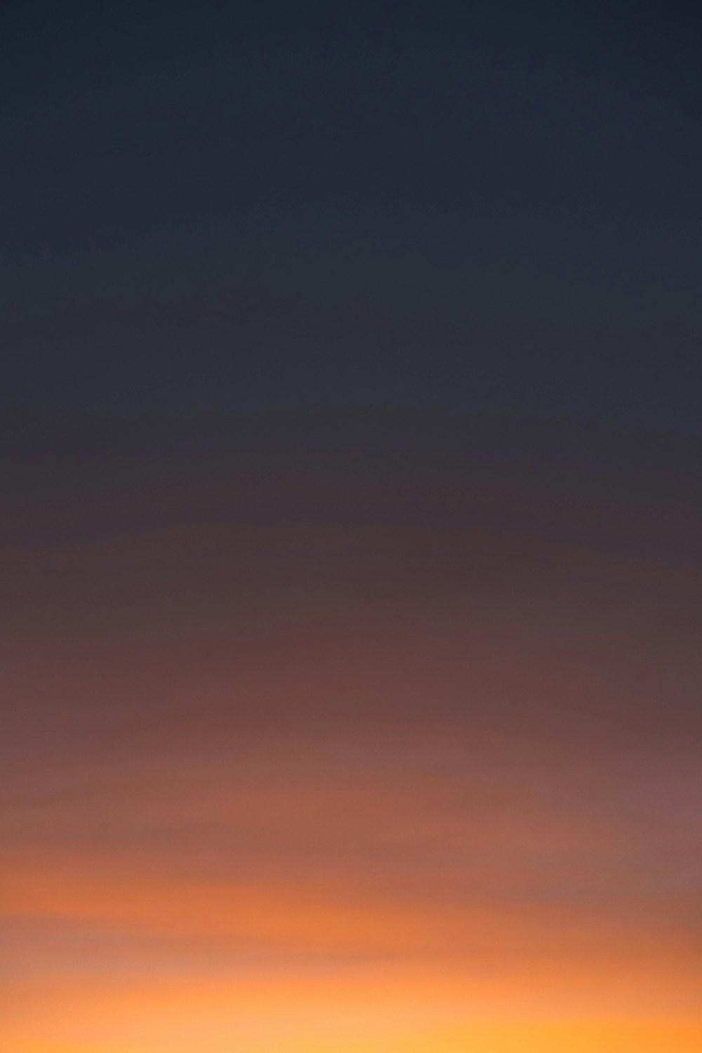 a plane flying in the sky at sunset