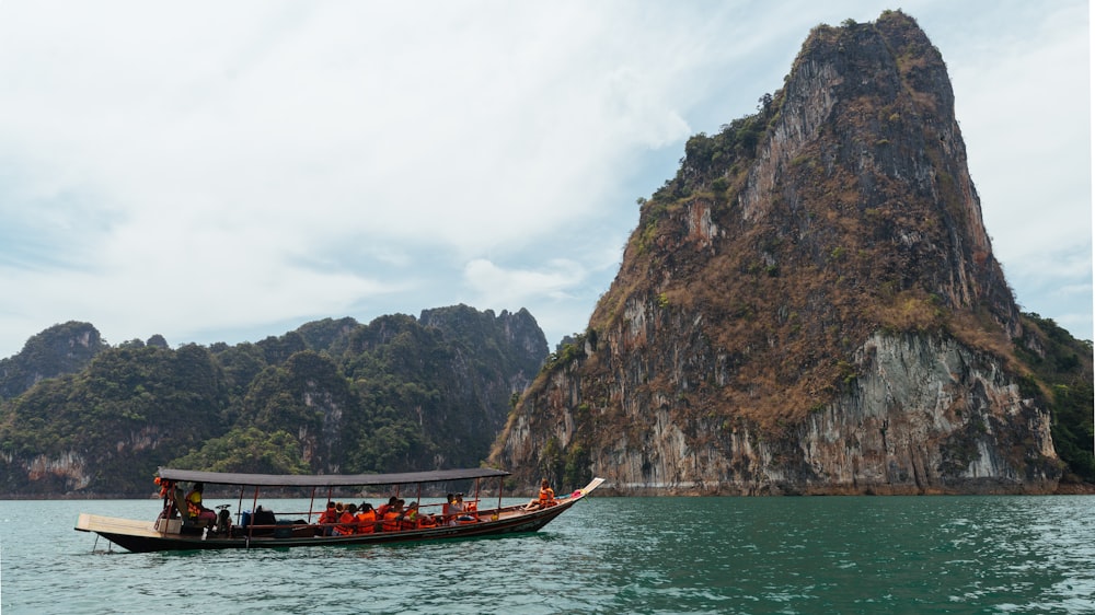 people riding boat near the mountain during daytime