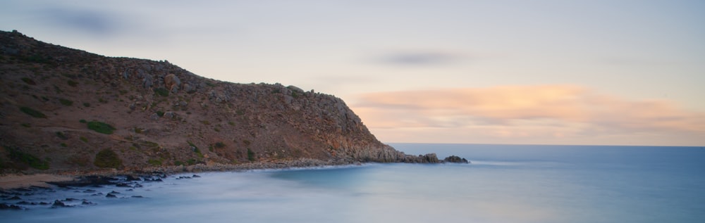 calm body of water near the mountain during daytime