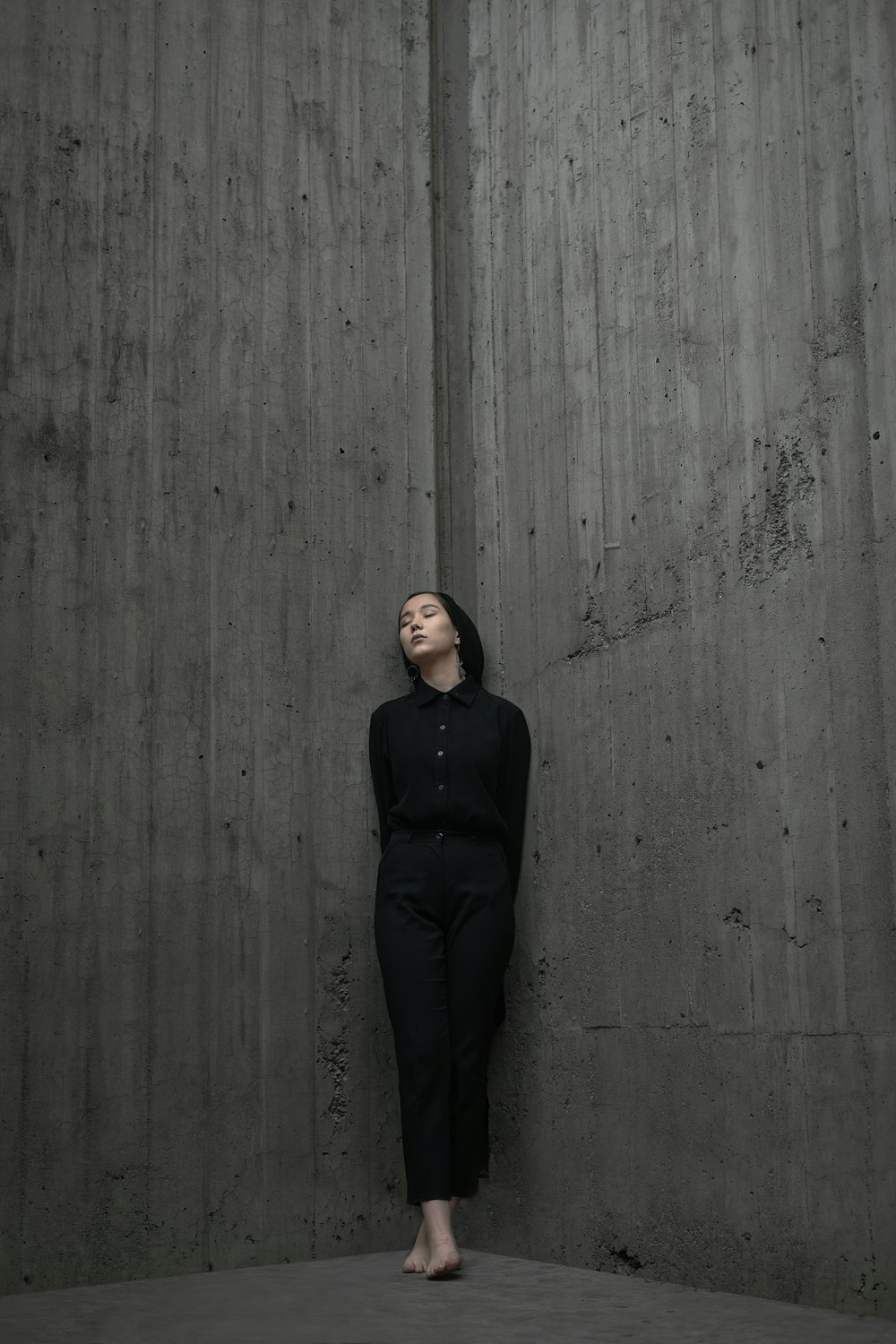 mulher em pé e apoiada no canto da parede de concreto