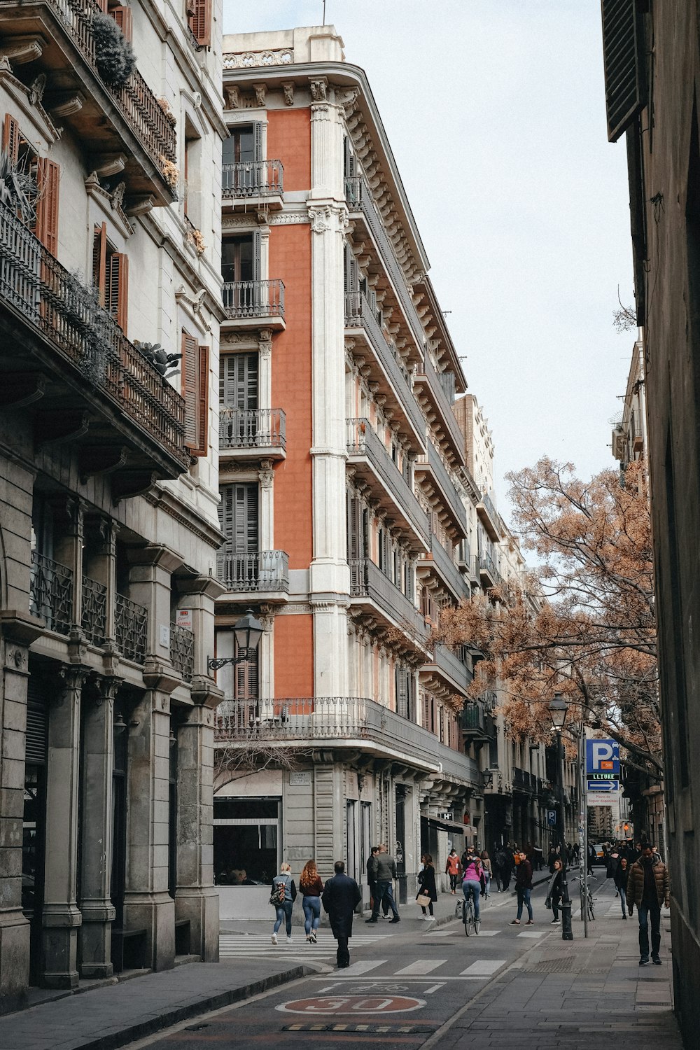 a group of people walking down a street next to tall buildings