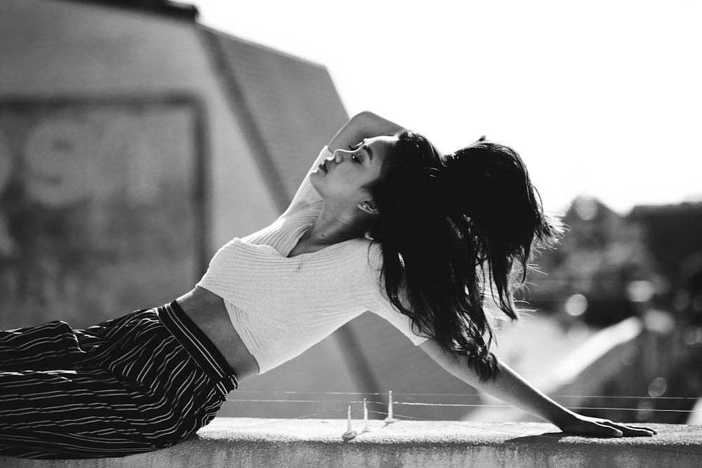 grayscale photo of woman lean on concrete wall