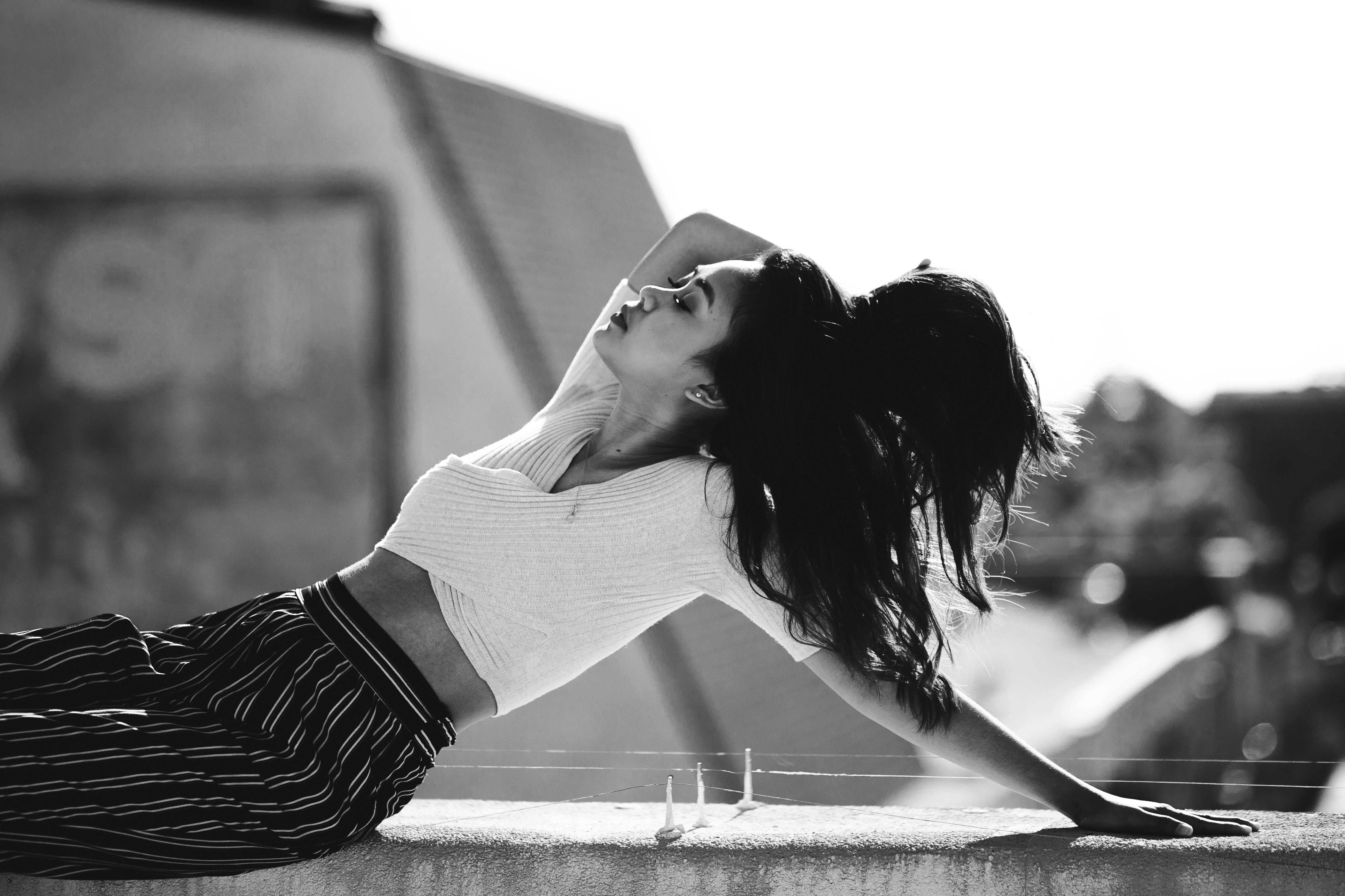 grayscale photo of woman lean on concrete wall