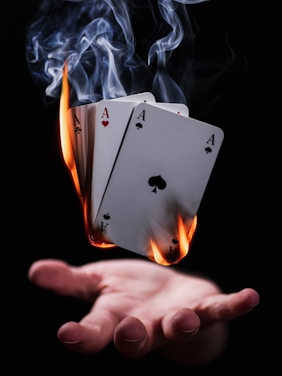 ein Stapel brennender Spielkarten schwebend über einer Hand