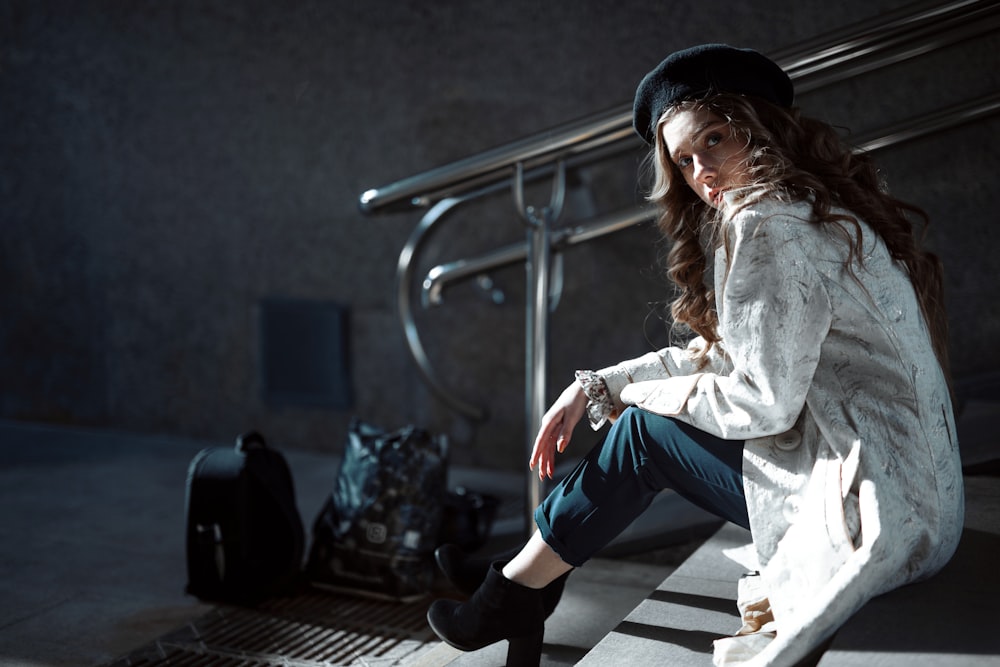 woman wearing white coat sitting on stair