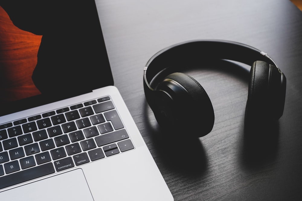 auriculares inalámbricos negros junto a la MacBook Pro