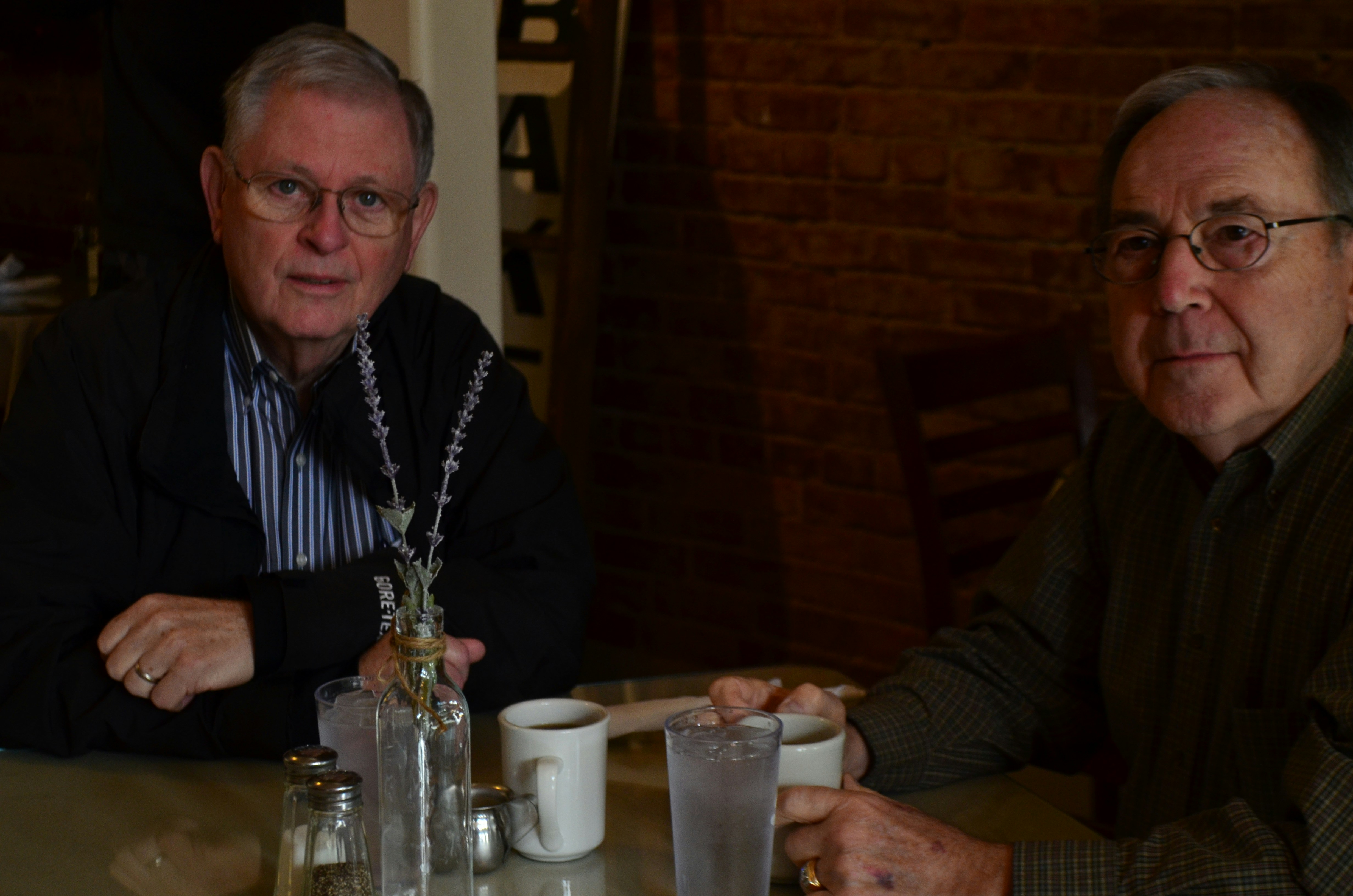 two men sitting holding mugs on table
