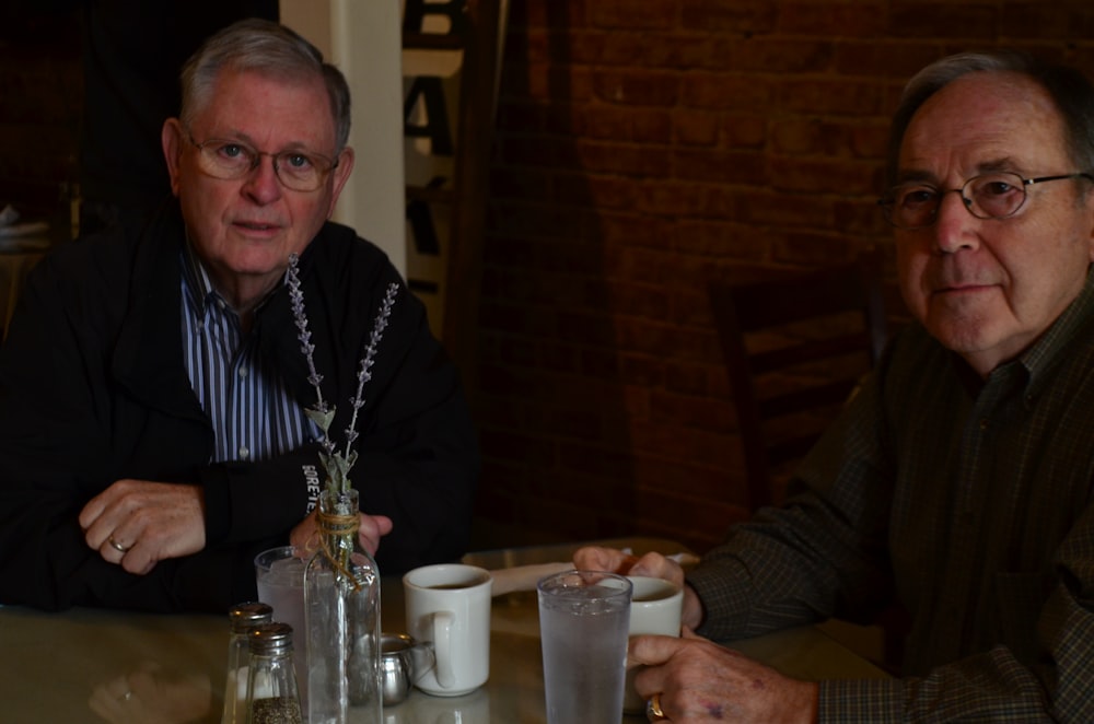 two men sitting holding mugs on table