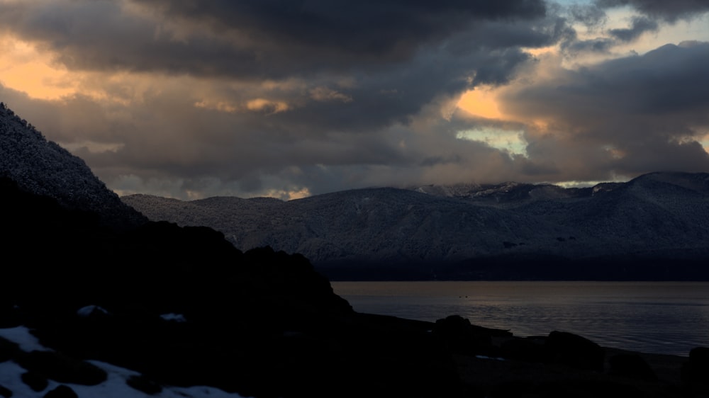 silhouette of mountain near sea during golden hour