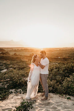 Sunlit outdoor portrait of a couple sharing a tender moment in a warm, sandy environment.