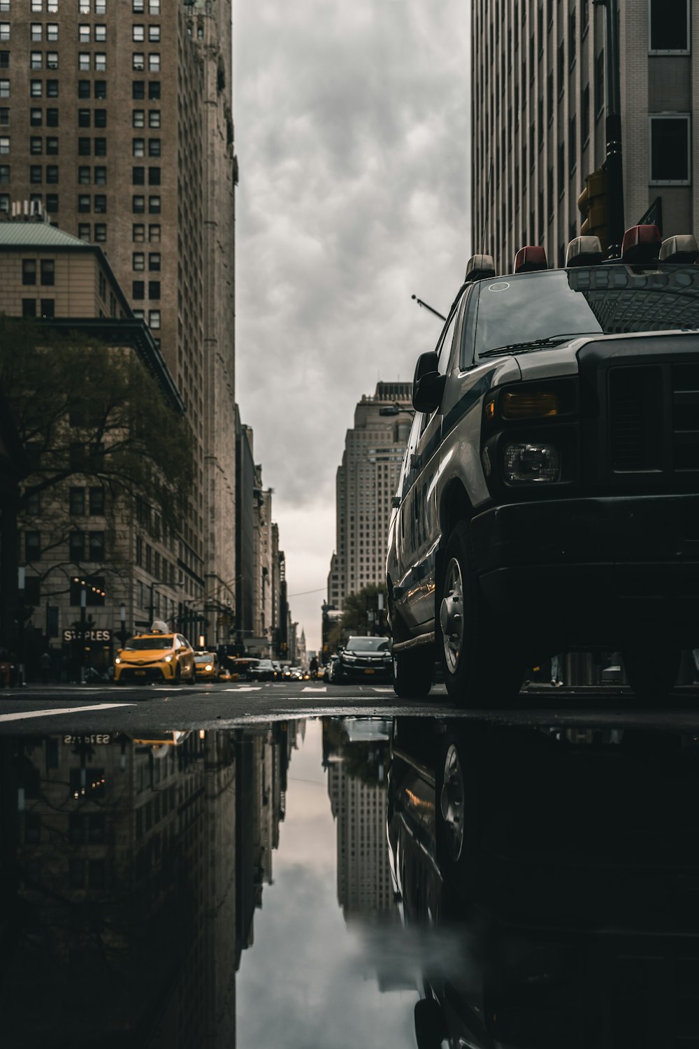 low angle photography of cars and building reflecting on body of water