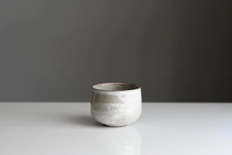 A minimalist tea cup set with a glossy glaze reflecting ambient light on a deep charcoal backdrop
