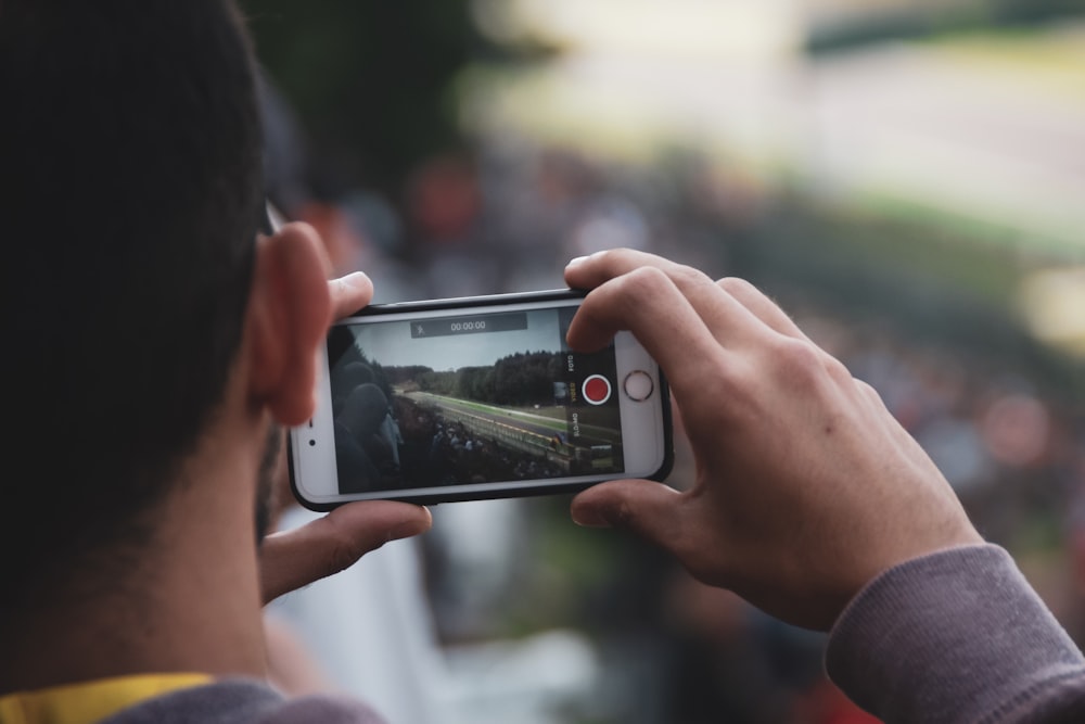 shallow focus photo of person taking photo using silver iPhone 6