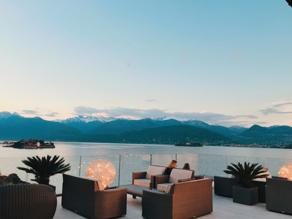 two people sitting on sofa on rooftop near ocean