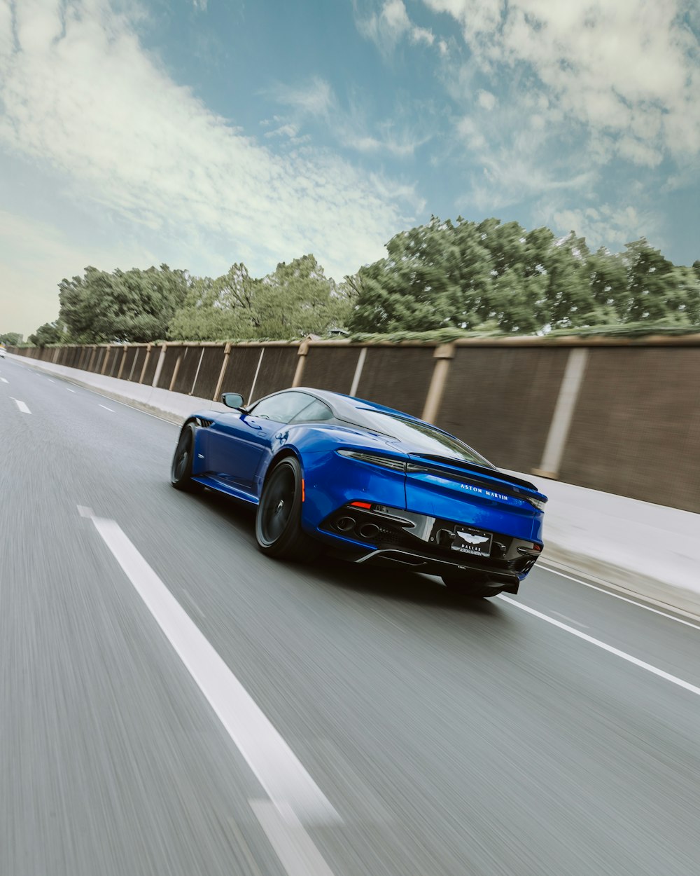 blue coupe passing by concrete road