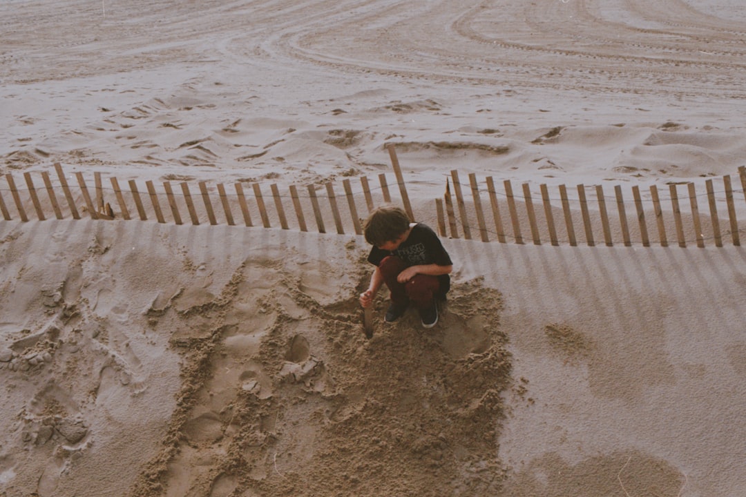 boy in black t shirt sitting on the sand