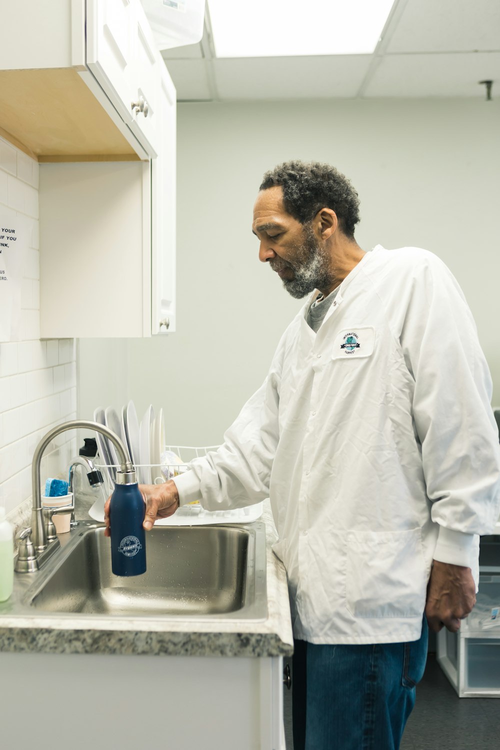 Mann mit weißem langärmeligem Hemd und Flasche in der Hand