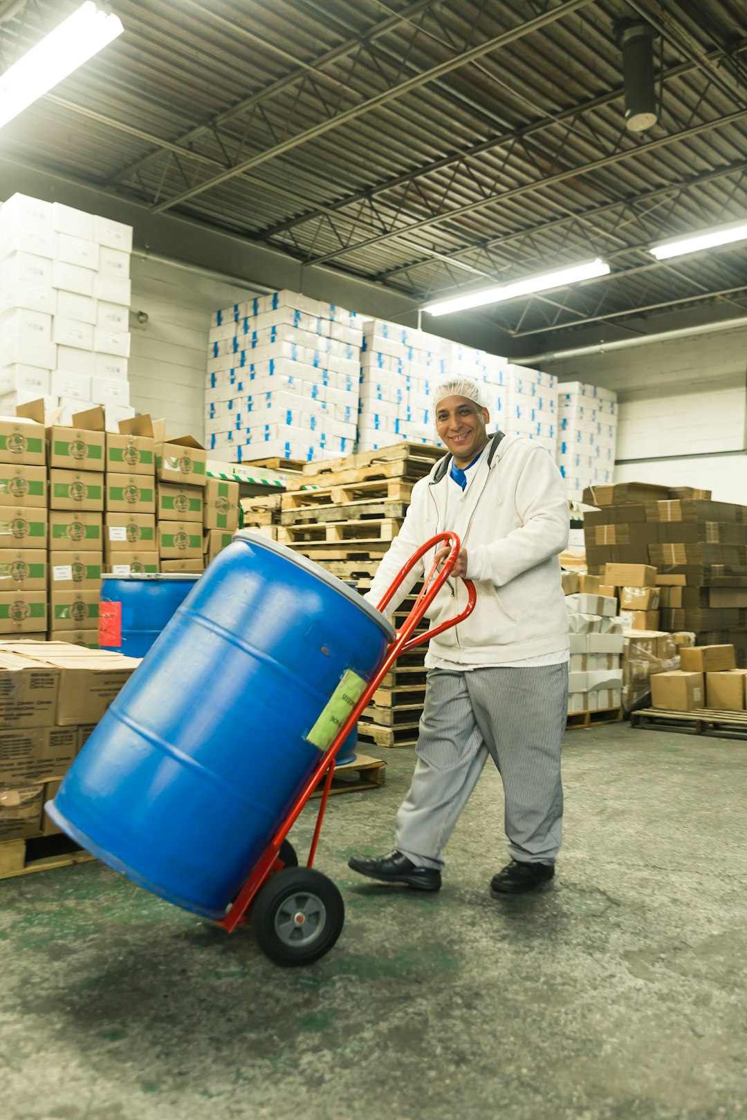 man pushing hand truck with plastic drum