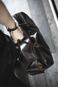 person holding brown leather handbag