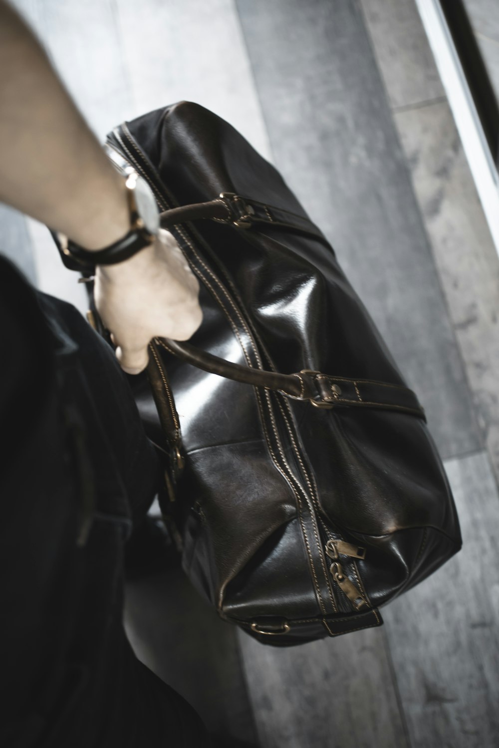 person holding brown leather handbag