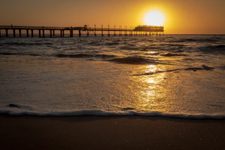 Sunset casting golden light over Eastbourne pier with gentle waves lapping the shore