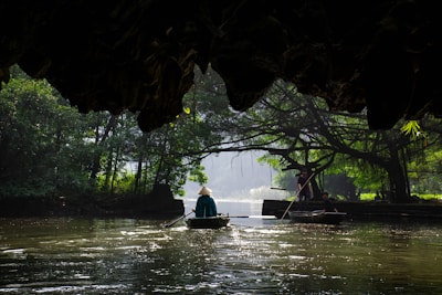 person sitting on boat surrounded with trees