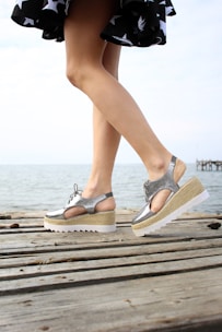 a woman standing on a wooden dock with her legs crossed