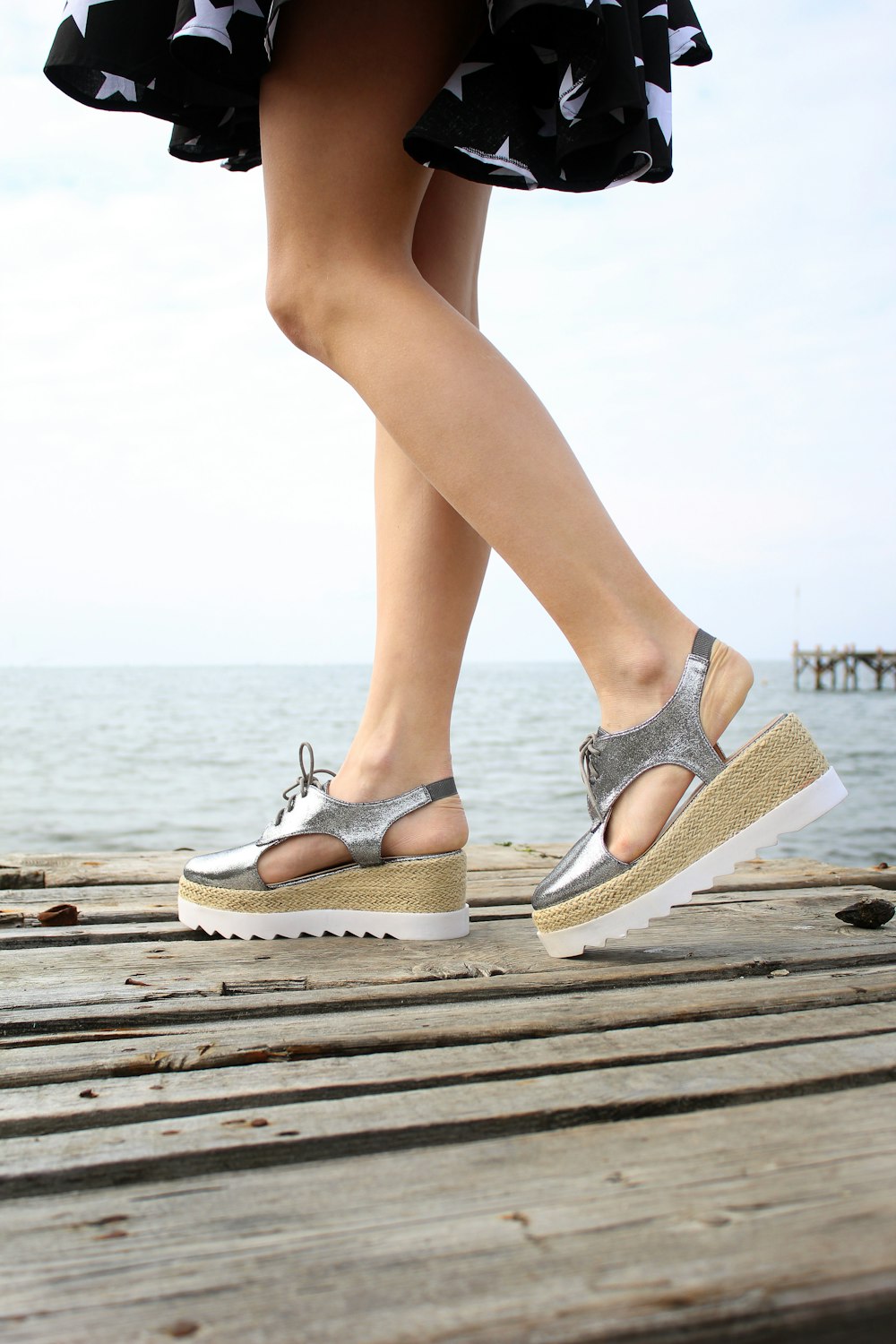 a woman standing on a wooden dock with her legs crossed