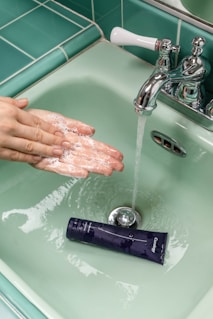 person washing hands on sink