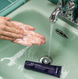 person washing hands on sink