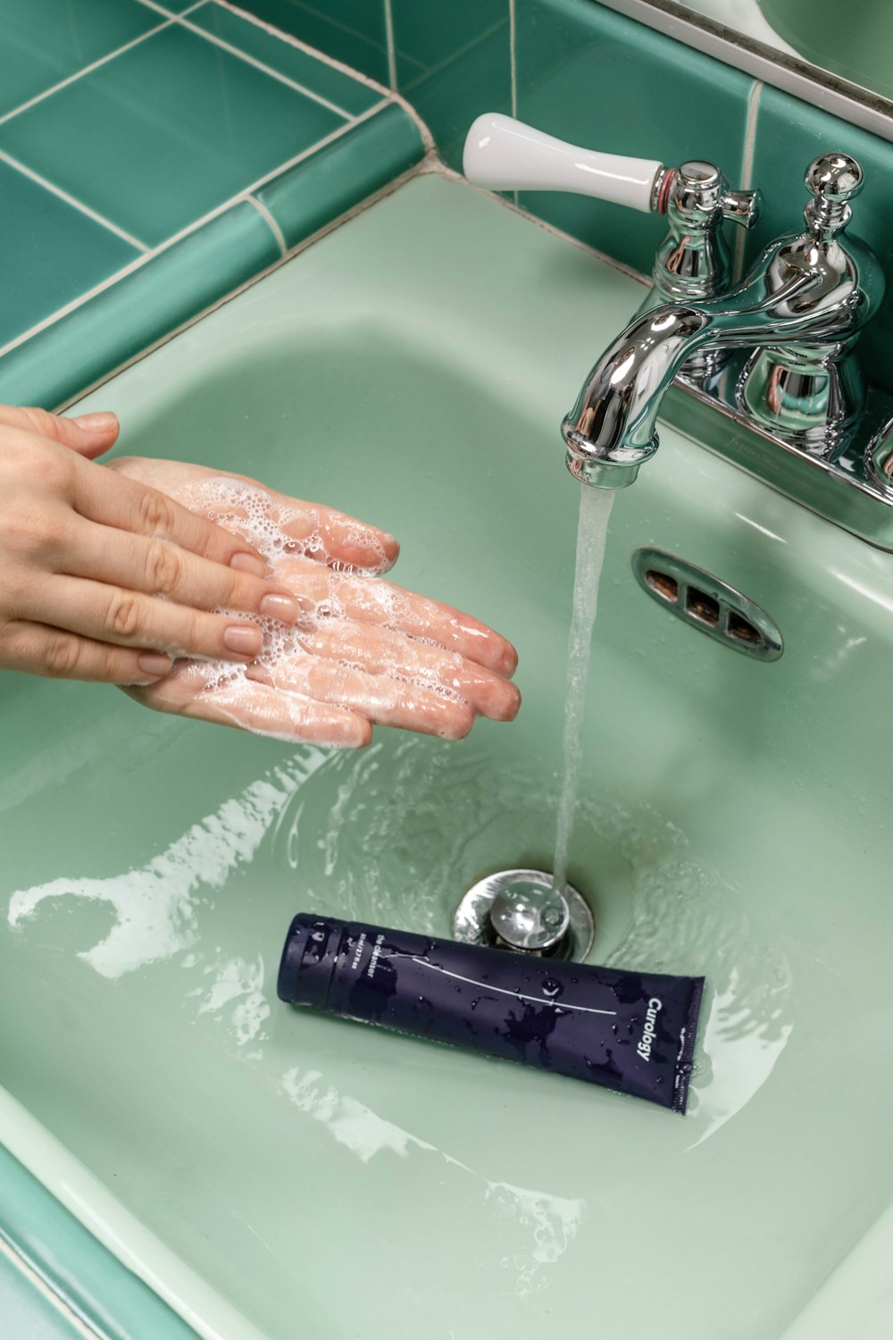 person washing hands on sink