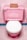 A pink toilet with a white seat is set against pink tiled walls and floor. On top of the toilet tank, there is a small, brown cardboard box.