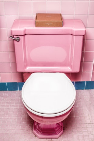 A sleek toilet lid covered with a plush, comfortable fabric cover in soft pastel colors.