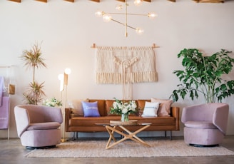 brown leather sofa and two pink sofa chair