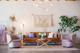 brown leather sofa and two pink sofa chair