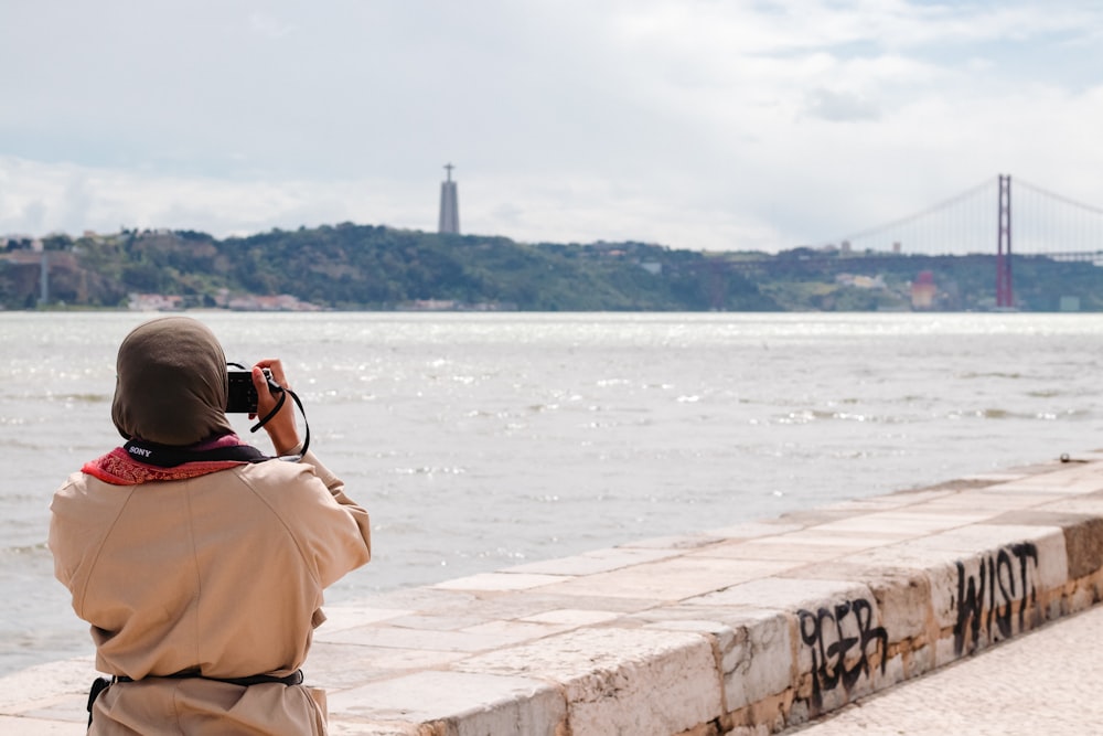 person taking photo of Golden Gate bridge in front of body of water