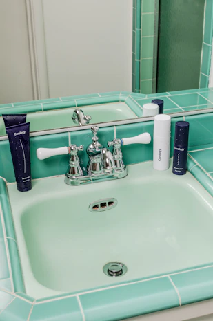 Bright and airy bathroom with sage green tiles and elegant gold fixtures.