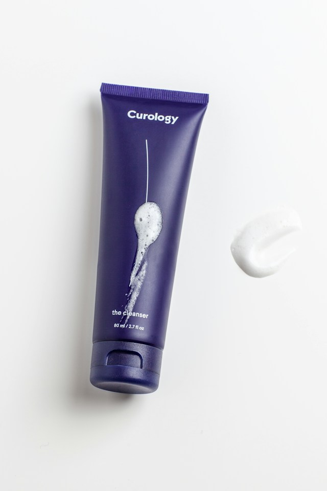 Violet-lit skincare jar on folded paper