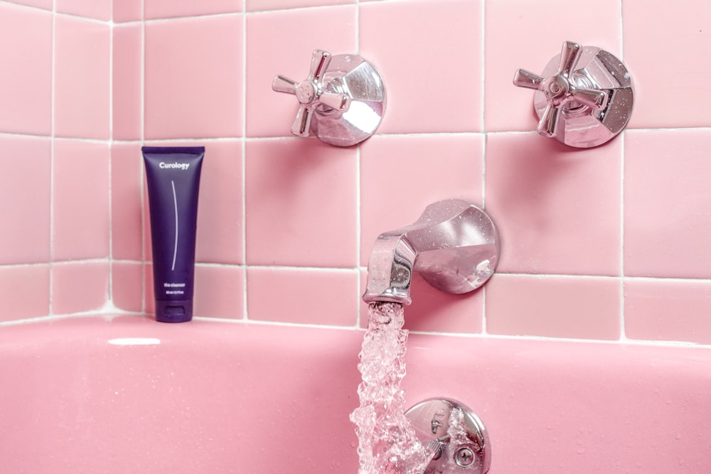 una vasca da bagno rosa con rubinetto e distributore di sapone