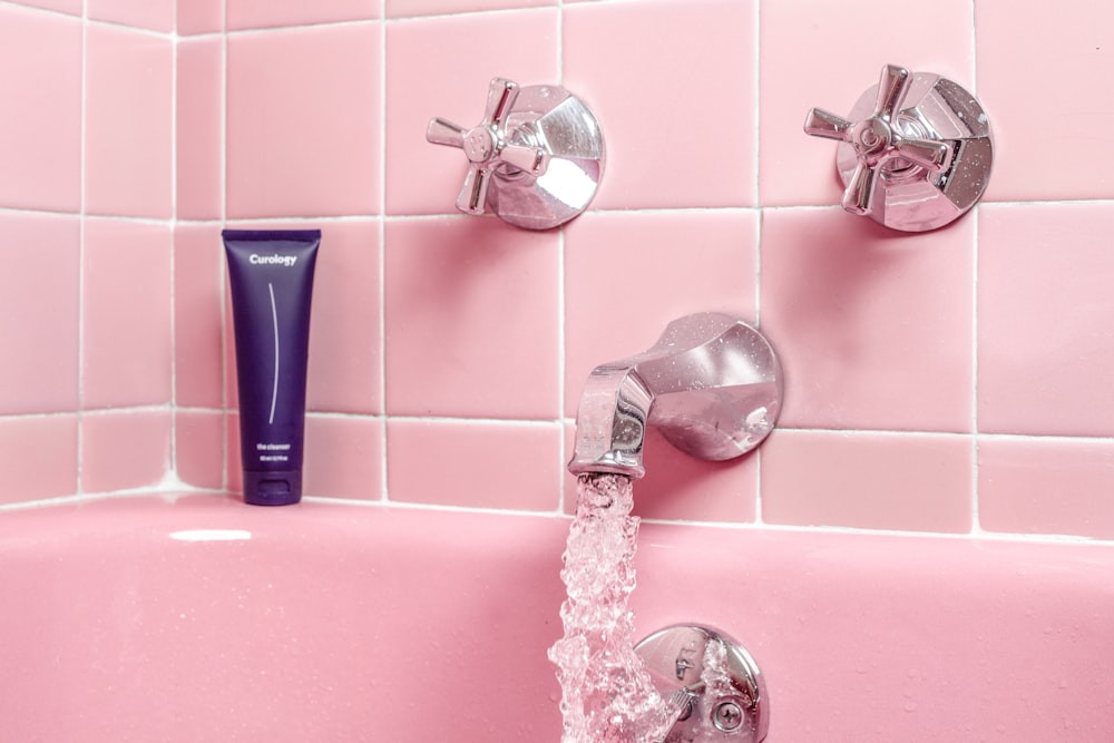 une baignoire rose avec robinet et distributeur de savon